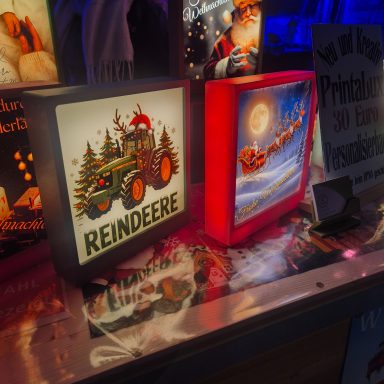 Leuchtende Dekorationen mit Rentieren und Weihnachtsmotiven auf beleuchtetem Tisch.