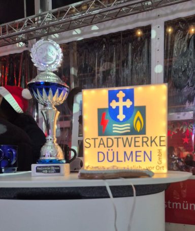Ein Pokal steht neben einem beleuchteten Schild mit der Aufschrift "Stadtwerke Dülmen".