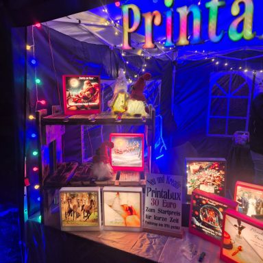 Bunte Lichter und Fotos in einem Kiosk mit dem Schriftzug "Prints".