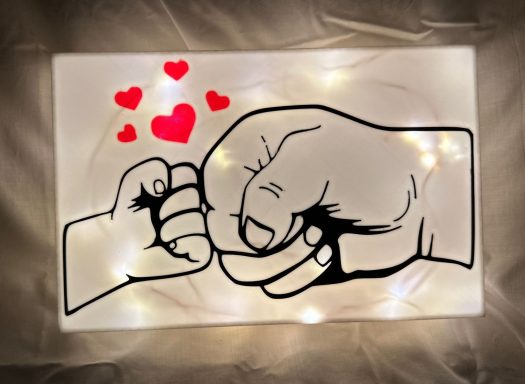 Eine große und eine kleine Faust geben sich ein Fistbump, umgeben von Herzen.