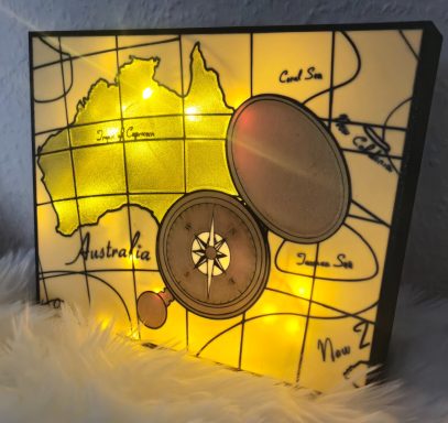 Deko-Lampe mit einer Karte von Australien und einem Kompass, beleuchtet mit warmem Licht.