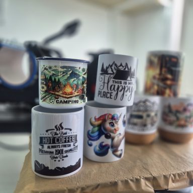 Verschiedene Tassen mit bunten Designs und Schriftzügen auf einem Tisch.