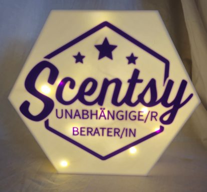 Hexagonales Schild mit dem Schriftzug "Scentsy" und "UNABHÄNGIGE/R BERATER/IN" in lila.