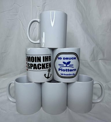 Weiße Tassenstapel mit verschiedenen Aufdrucken, darunter "Moin" und ein Anker.