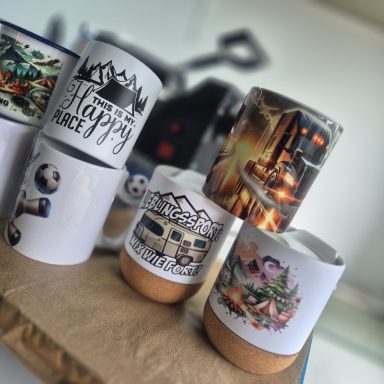 Mehrere Tassen mit verschiedenen Designs, darunter Landschaften und Grafiken.